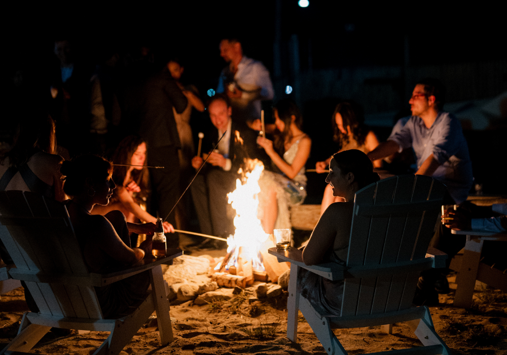 Wedding guests gathered around a beach bonfire at The Point at Norwalk Cove in Norwalk, Connecticut.