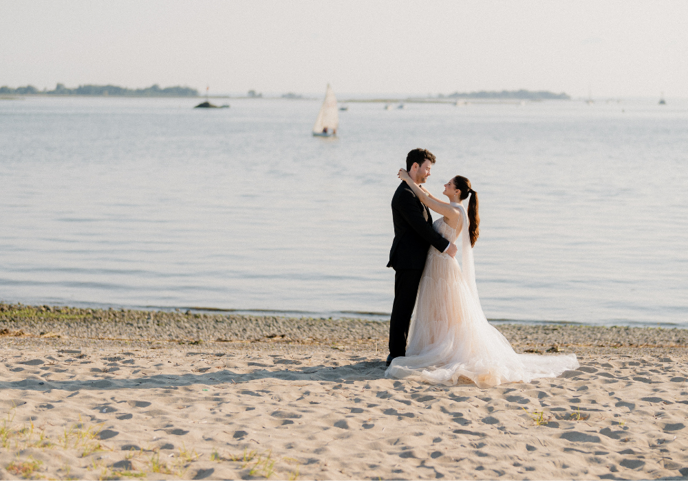 Bride and groom on the beach at The Point at Norwalk Cove, a waterfront wedding venue in Fairfield County, Connecticut.