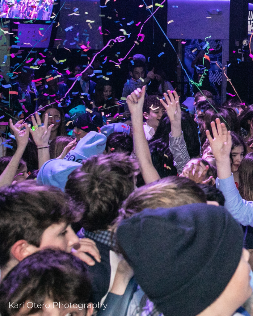 Teens celebrating a Bat Mitzvah in Westchester with a confetti drop on a crowded dance floor.