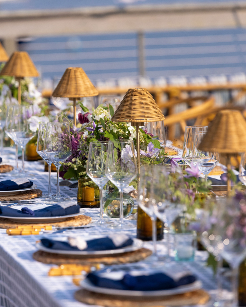 Close-up of a bespoke wedding menu table setting with wicker lamps and artisanal floral arrangements for a Westchester event.
